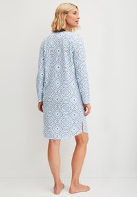 Abito blu a fantasia con maniche lunghe, caratterizzato da un design floreale, dettaglio con spacco frontale e una consistenza del tessuto morbida, visto da dietro.