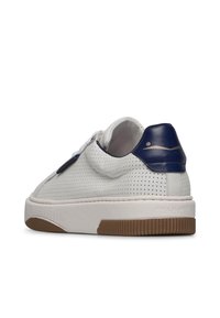 Sneaker in pelle perforata bianca con accento blu scuro sul tallone, suola in gomma bianca e suola in gomma testurizzata. Presenta una cerniera laterale per la chiusura.