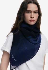 Marineblå plisseret tørklæde lavet af et struktureret stof med subtil glans og et elegant design. Håndskrevet accent i hvid.