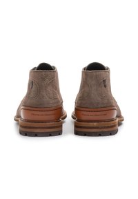 Botas de tobillo de ante marrón con un acabado texturizado, paneles laterales elásticos y acentos de cuero en el tacón. Suela de goma con un patrón de relieve.