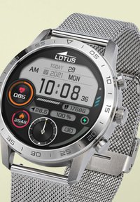 Srebrna pametna ura s okroglo številčnico. digitalni zaslon prikazuje čas, datum, srčni utrip in podrobnosti o telesni pripravljenosti. Mrežna zapestnica in ohišje iz nerjavnega jekla.