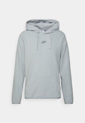 Jasnoszara bluza z kapturem Nike z polaru, z przednią kieszenią typu kangur oraz regulowanym sznurkiem w kapturze, prezentowana na białym tle.