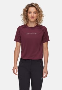 Kortärmad vinröd teknisk tröja i fukttransporterande tyg med logotyper och reflexdetaljer, ihop med mörka byxor.