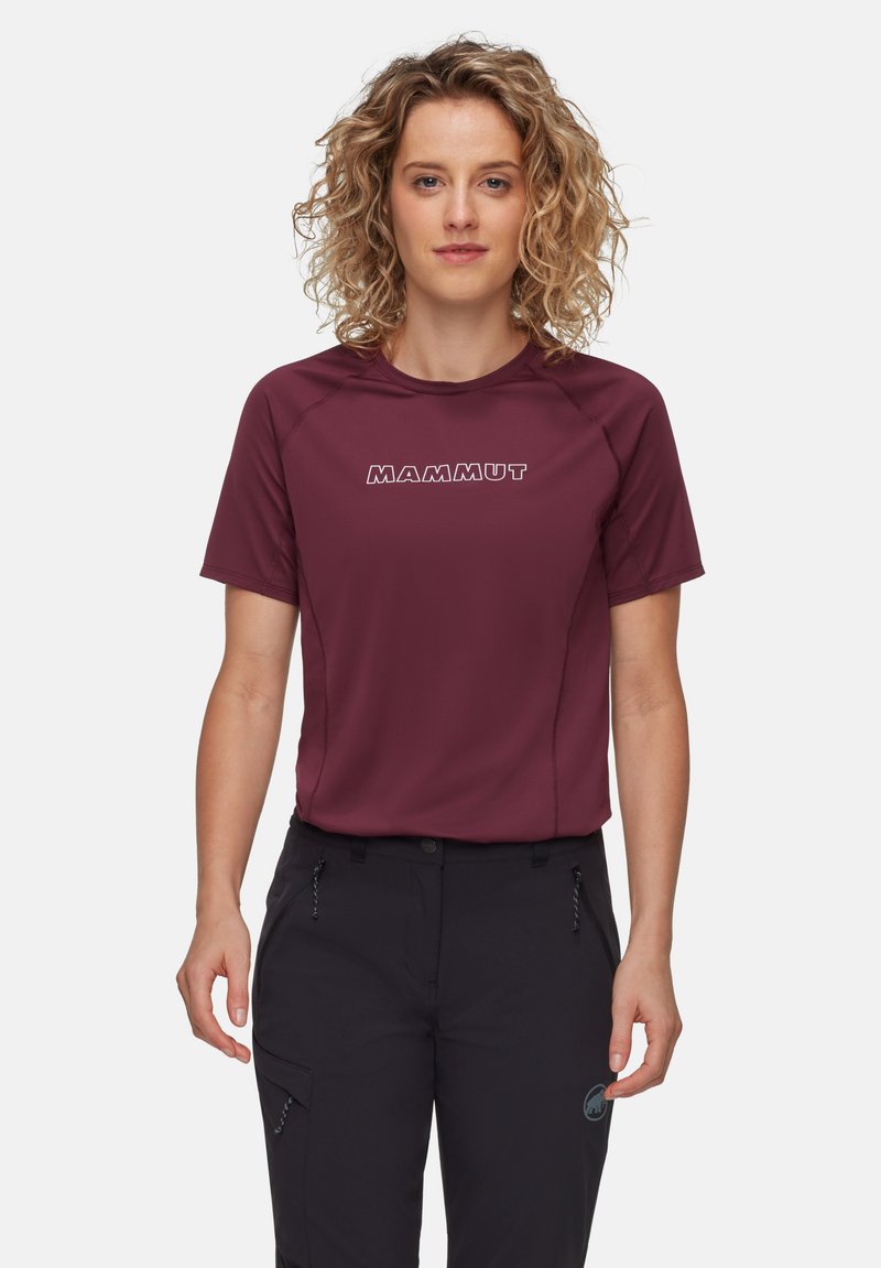 Kortärmad vinröd teknisk tröja i fukttransporterande tyg med logotyper och reflexdetaljer, ihop med mörka byxor.