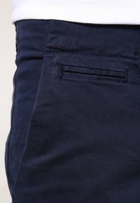 Sjöblå byxor i ett smidigt material, med en diskret sidficka och en skräddarsydd passform med rak bendesign.