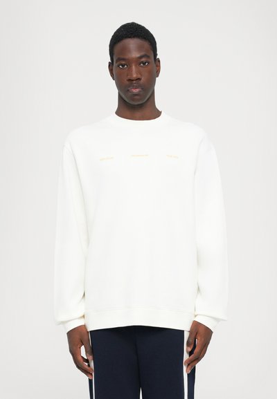 Witte crewneck sweatshirt van een katoenmix. Bevat gouden tekst aan de voorkant. Losse pasvorm met ribgebreide manchetten en onderkant. Draagt zich met donkere broeken.