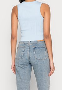 Ljusblå ribbad korthylsad topp med rund halsringning, i kombination med högmidjade urtvättade blå jeans med bakfickor och ljusa sömmar.