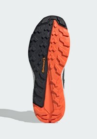 Sål med en sort og orange gummimønster med hexagonale og zigzag mønstre, designet til trækkraft og holdbarhed.