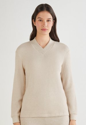Pull beige côtelé avec un col en V, des manches longues et une texture douce. Le col est d'une teinte plus claire, complétant ainsi le design global.