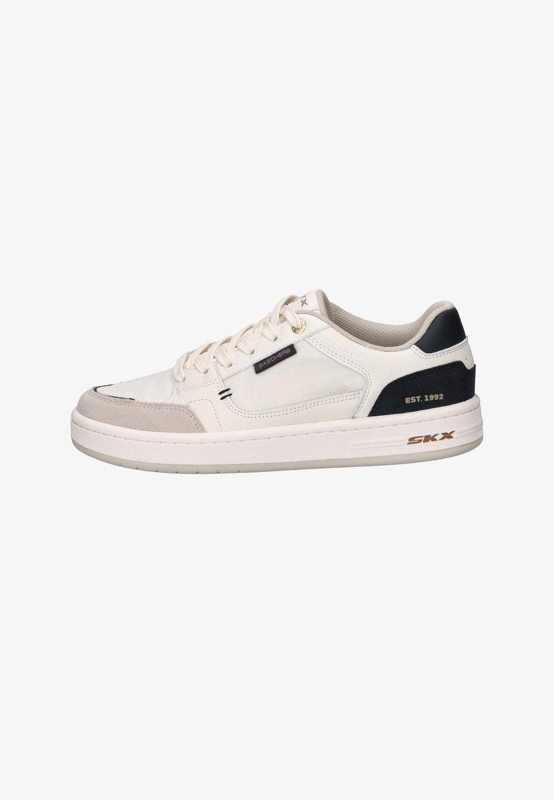 Low-top beige sneaker with white sole, black heel panel labeled "EST. 1992," and small "Skechers" tag on side.