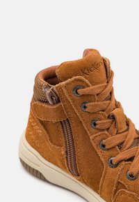 Baskets montantes en daim marron avec des accents en maille, lacets ronds, détail de fermeture éclair sur le côté et une semelle en caoutchouc avec un motif strié.