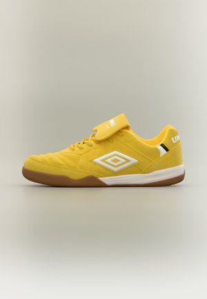 Gul Umbro indendørs fodboldsko med hvidt logo, gummisål og velcrorem over snørebåndene mod en neutral baggrund.