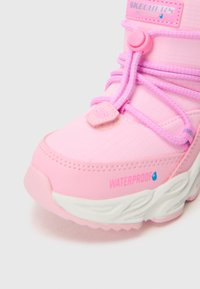 Sapatilha impermeável rosa com um cabedal sintético texturizado, bico arredondado, atacadores elásticos e uma sola branca com padrões ondulados.