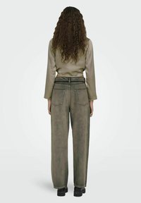 Olivengrøn, højtaljede jeans med lige benpasform, der har baglommer og en tekstureret overflade. Sammen med en satin top med lange ærmer.