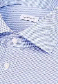 Chemise habillée à carreaux bleu et blanc avec un col boutonné, arborant une étiquette indiquant "seidensticker" et une texture lisse.