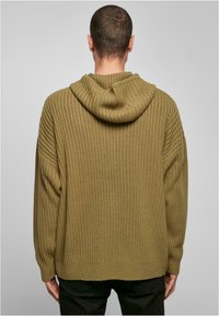 Oliven grønn hettegenser med ribbestrikket tekstur og løs passform, med rund hette, drop shoulders og en avslappet nederkant.