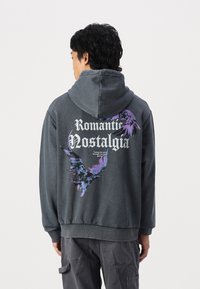 Dark gray hoodie with a front kangaroo pocket, featuring a colorful graphic of birds and text "Romantic Nostalgia" on the back.