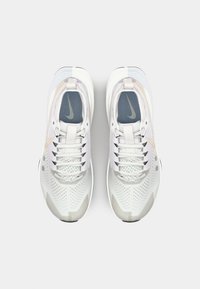 Sportschuhe mit einem hellgrauen Synthetikoberteil, grauem Netz-Zungen und weißen Sohlen. Verfügt über Perforationen und ein dezentes beige Designakzent.