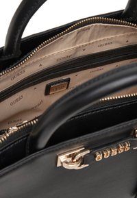 Borsa a tracolla nera in pelle con hardware dorato, chiusura a zip e fodera interna con marchio. Presenta manici robusti e scomparti spaziosi.