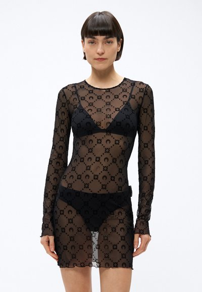 Durchscheinendes schwarzes Kleid mit langen Ärmeln, verziert mit einem Blumenmuster. Schwarze Unterwäsche ist unter dem transparenten Stoff sichtbar.