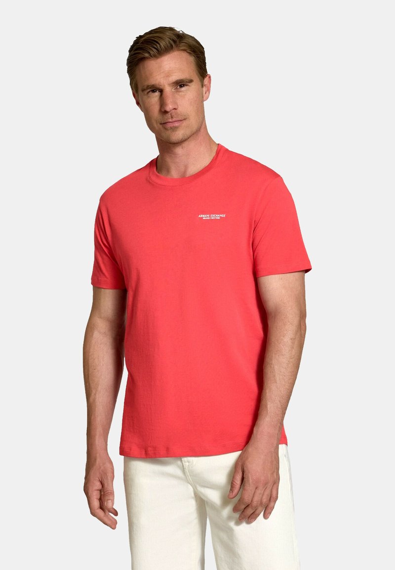 Tricou din bumbac coral, cu guler rotund, maneci scurte și un mic logo alb pe pieptul stâng. Textură netedă, croială casual.