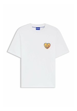 Hvid T-shirt med korte ærmer og rund hals med lille orange hjerte-patch, der har et blåt smilende ansigt og teksten "HUGO" på brystet.