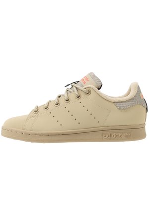 Beige Adidas Stan Smith sneaker med snørelukning, perforerede tre striber og tekstureret krave-detalje.