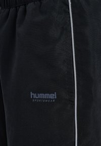Svarta sportshorts i lättviktsmaterial med elastisk midjeresår, med Hummel-logotyp och en kontrasterande silverrand.