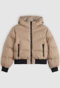 Chaqueta acolchada beige con capucha, que cuenta con un cierre frontal, dos bolsillos laterales con cremallera y puños y dobladillo de canalé negro. Patrón de acolchado en forma de flecha.