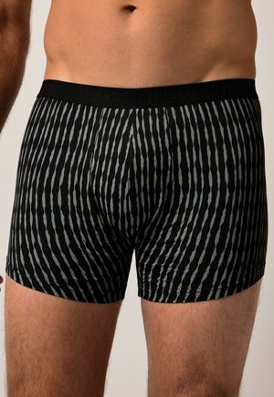 Bóxer negro con un patrón de rayas verticales en gris. Hecho de tela suave con una cintura elástica que muestra el nombre de la marca.