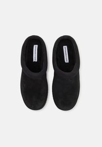 Zuecos de ante negro con un diseño redondeado, abertura amplia y textura suave. Acentuados con un cuello elástico y liso para facilitar el uso.