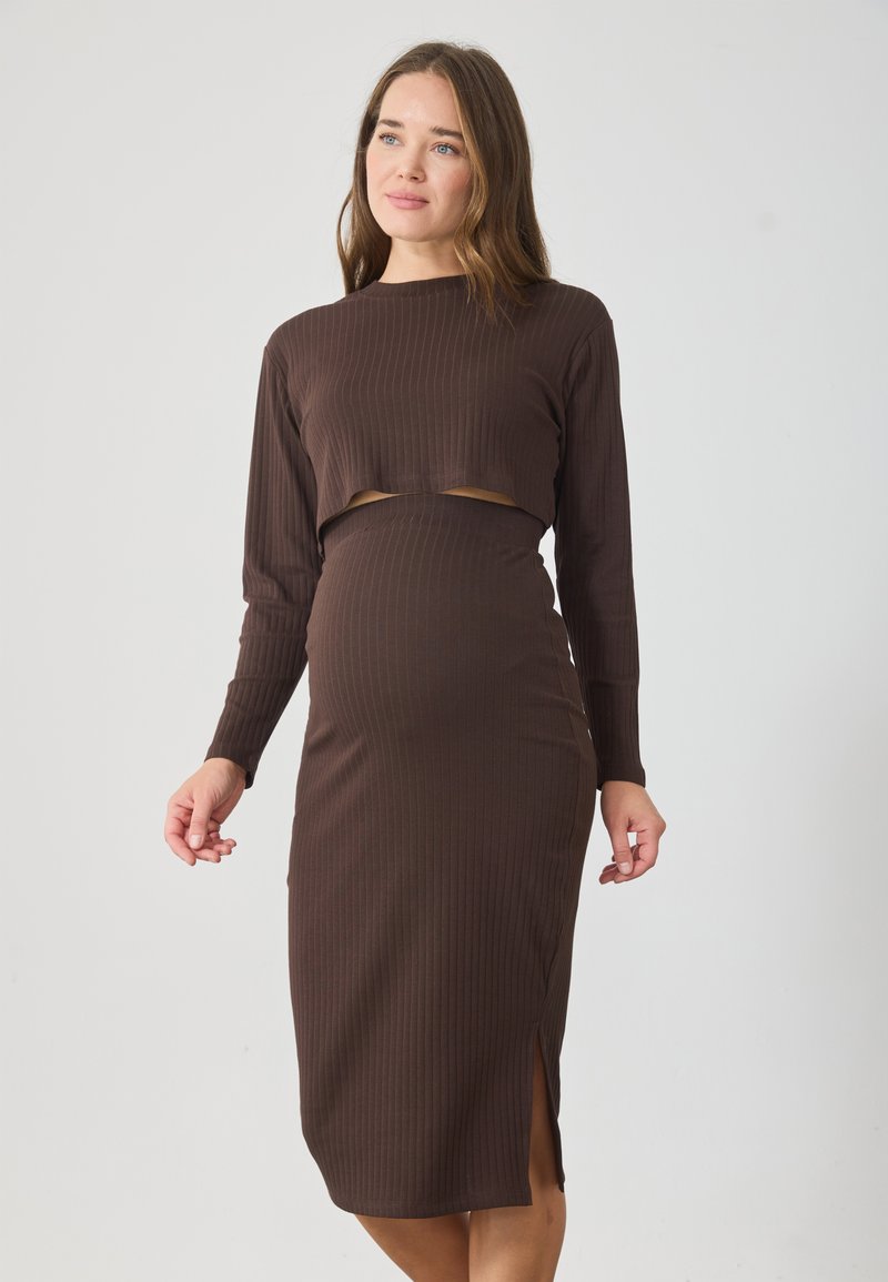 Maternitātes kleita tumši brūnā ribota audumā, ar garām piedurknēm, īsu augšu ar izgriezumu un tūlītējo garumi ar sānu šķēlumu.