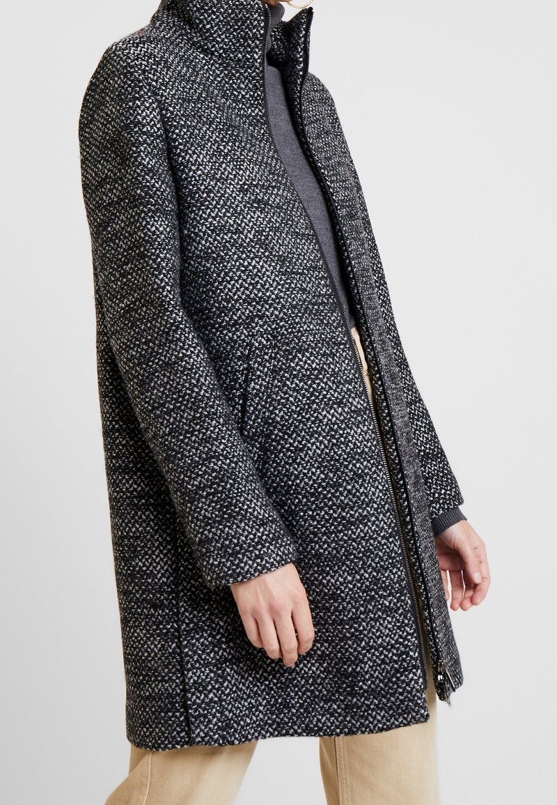 Cappotto in misto lana con colletto alto, motivo grigio-nero testurizzato, chiusura con zip e tasche laterali. Design minimale con taglio dritto.