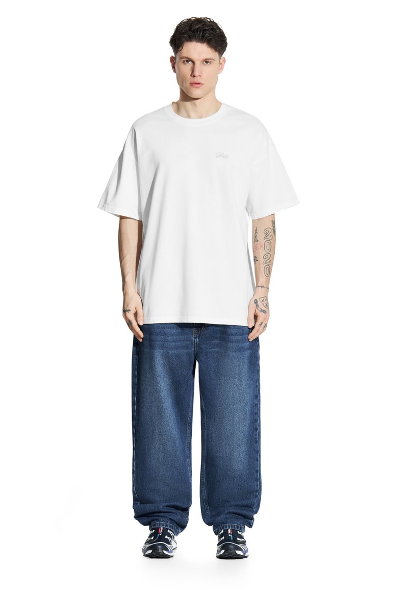 Biała bawełniana koszulka z krótkimi rękawami, w połączeniu z luźnymi granatowymi dżinsami. Sneakersy z czarno-białymi akcentami.