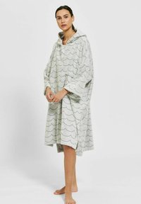 Huvtröja i ljusgrått, tillverkad av mjukt tyg, med ett vågmönster. Löst sittande med vida ärmar och sidofickor.