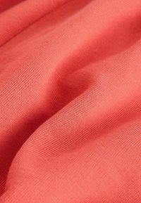 Mäkká ružová korálová pletenina s jemnou rebrovanou textúrou a jemnými záhybmi.