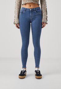 Vaqueros skinny de mezclilla de color azul, con cintura alta, diseño de cinco bolsillos y un ligero estiramiento para mayor comodidad.