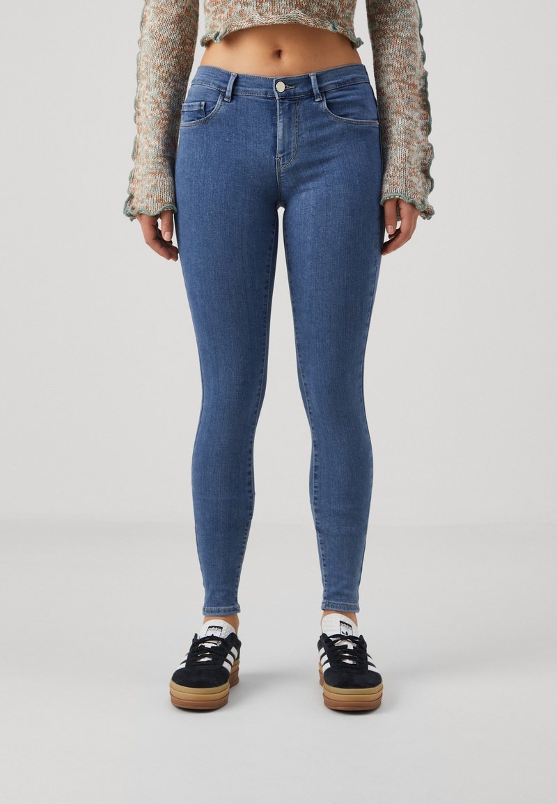 Vaqueros skinny de mezclilla de color azul, con cintura alta, diseño de cinco bolsillos y un ligero estiramiento para mayor comodidad.