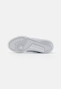 White rubber shoe sole featuring textured grip patterns and an embossed logo. Smooth grey upper with perforations for breathability.
