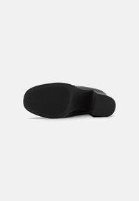 Black shoe sole with a flat, smooth design. Features horizontal grooves for traction and a rounded toe. Made of durable rubber material.