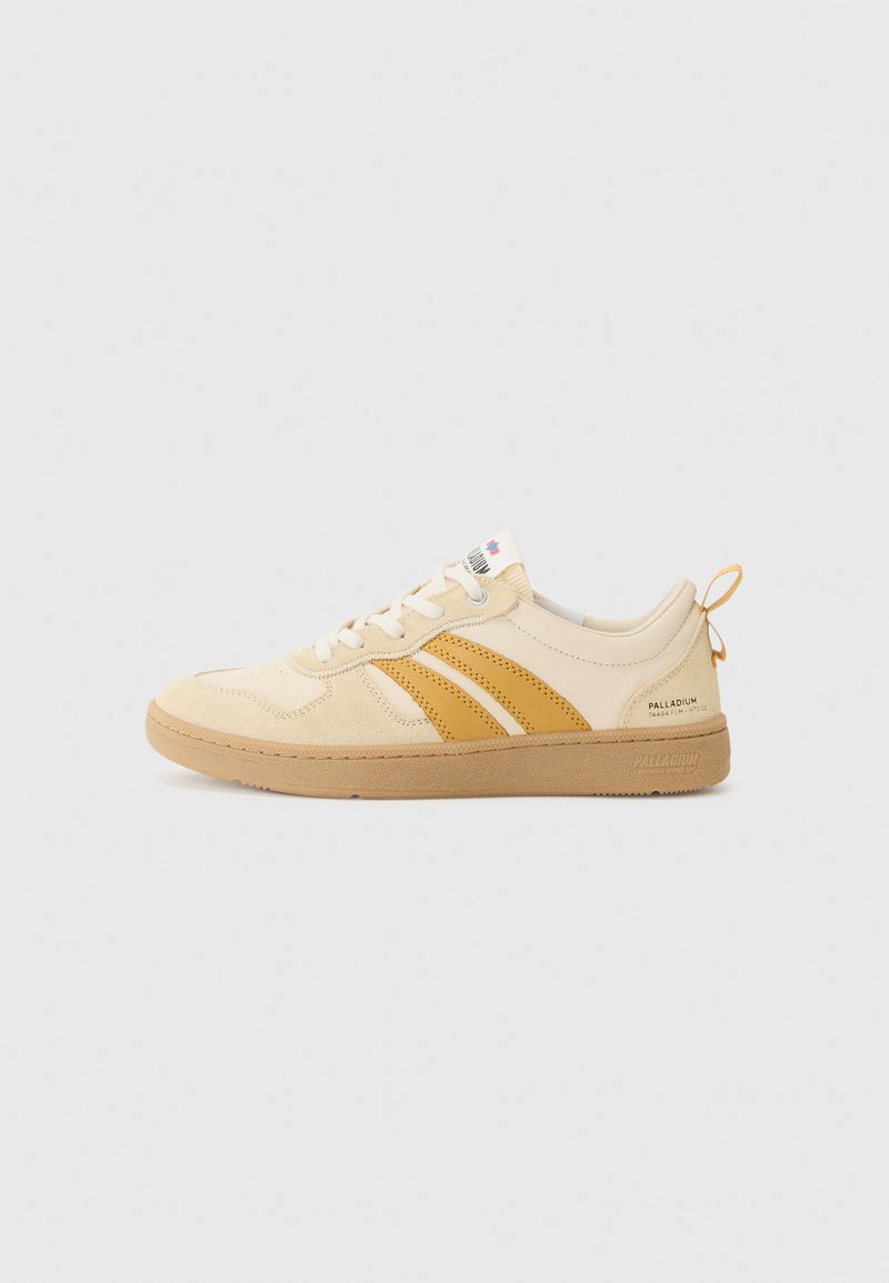 Beige joggesko med brune detaljer, overdel i semsket skinn og mesh, flate lisser, gummisåle og en bakre løftestropp. Har tre vertikale striper.