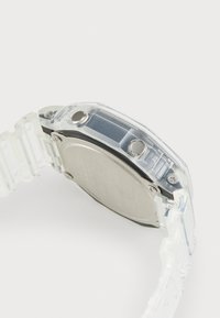 Clear plastic watch featuring a silver stainless steel back, two buttons, and a segmented strap. Clean lines and minimalist design.