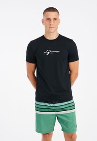 Zwart T-shirt met korte mouwen en een wit logo in het midden, gecombineerd met groene zwembroek met horizontale zwart-witte strepen.