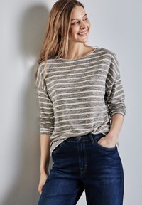 Lichtgewicht, grijs en wit gestreept langslijftop met een bootnek; gecombineerd met donkerblauwe, rechte jeans. Soepele textuur, casual pasvorm.