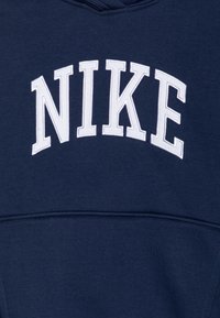 Sudadera azul marino con un destacado logotipo bordado en blanco de "NIKE" en el pecho. Fabricada en un suave tejido texturizado.