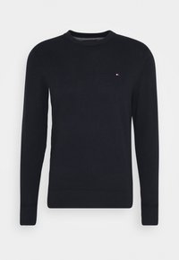 Maglione nero lavorato a maglia con scollatura rotonda e maniche lunghe, arricchito da un piccolo logo sul petto. Texture liscia e design aderente.