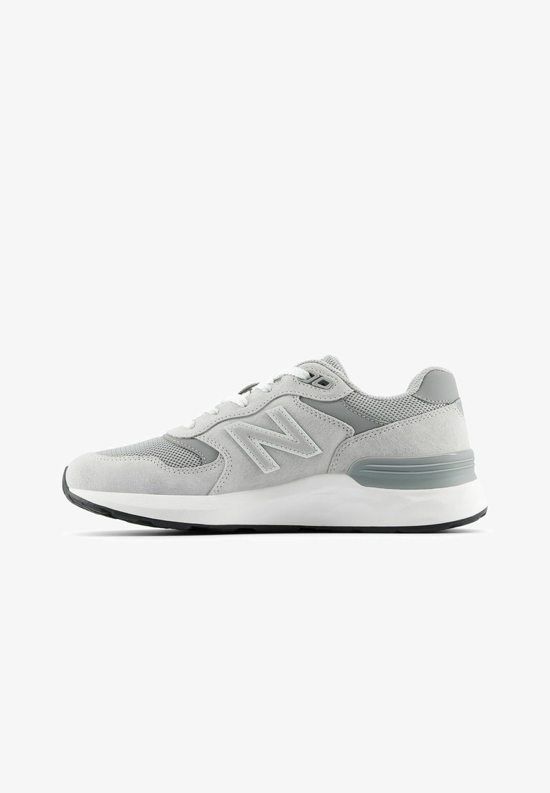 Basket New Balance gris clair avec panneaux en daim et mesh, lacets blancs, semelle amortie et semelle extérieure noire, vue latérale sur fond blanc.