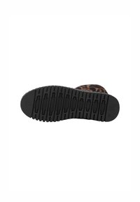 Suela de zapato de goma negra con superficie texturizada y patrones elevados. Presenta crestas para un mejor agarre y detalles de marca moldeados.