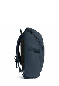 Zaino blu scuro con un design elegante e strutturato. Presenta spallacci imbottiti, piccole tasche con zip e un pannello laterale testurizzato.