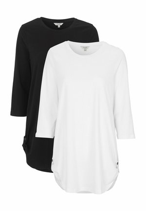 Zwei T-Shirts mit dreiviertel Ärmeln, eines schwarz und eines weiß, aus weichem Stoff mit abgerundetem Saum und Knopf-Akzenten an den Seiten.